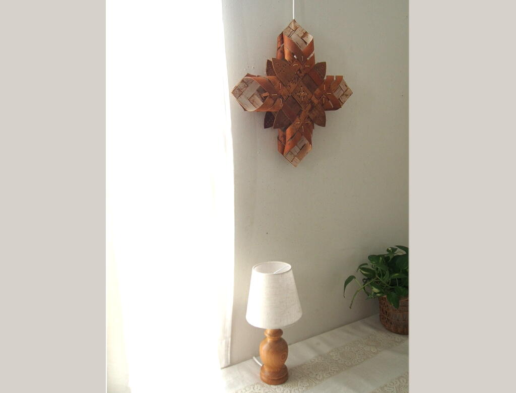白樺を編んで形づくられたオーナメントランプ。木のあいだからやわらかな光がこぼれ、部屋に穏やかなぬくもりを添える灯り。