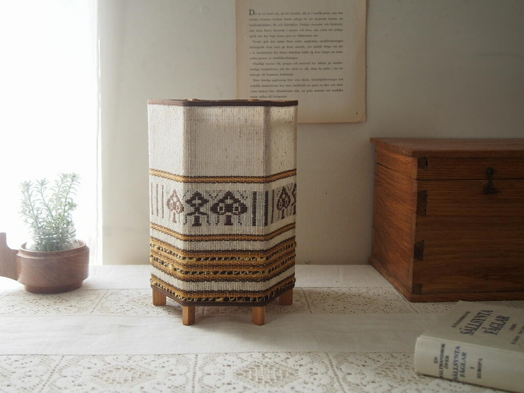 無垢材の枠組みと刺しゅうシェードが見えるテーブルランプ。落ち着いた生成りとブラウンの配色。 antenna