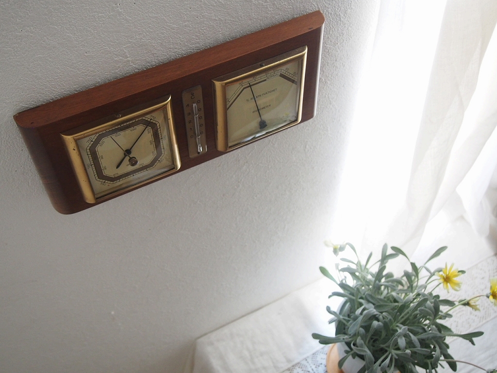 光を受けて並ぶヴィンテージの温度・気圧・湿度計。木製フレームが静かな存在感。 antenna