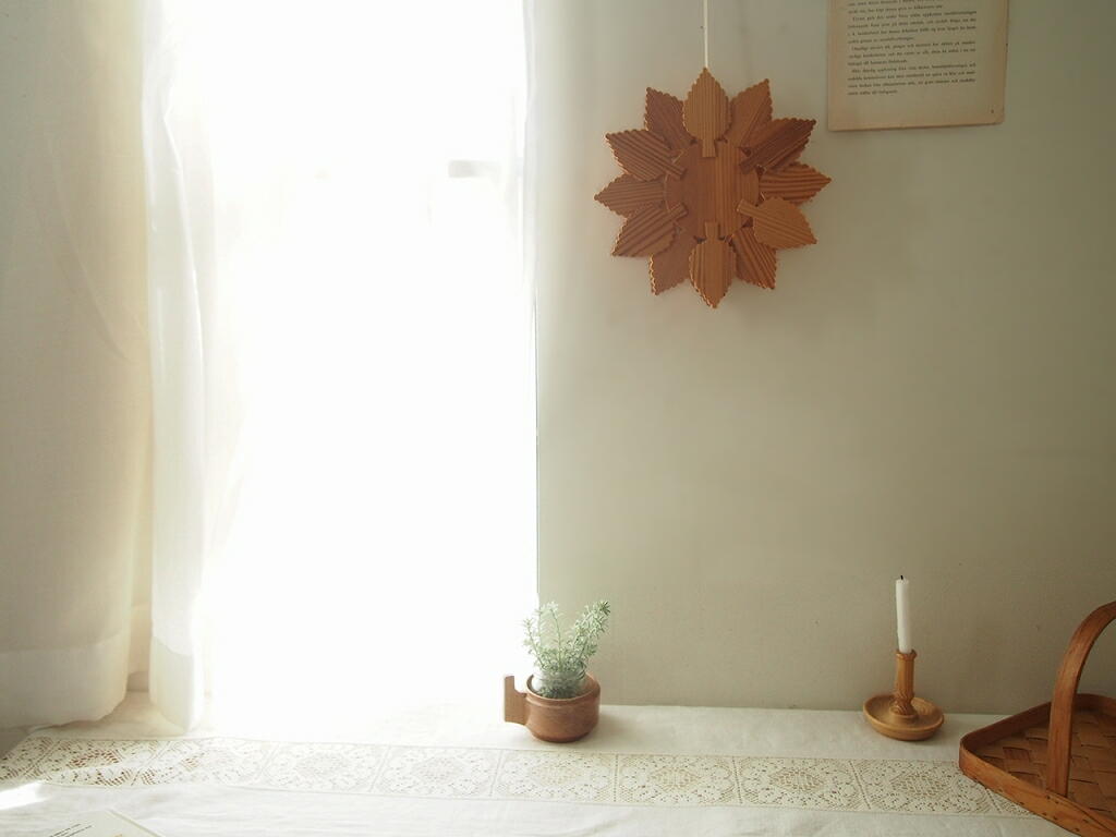 壁に吊るした木製オーナメント。やさしい光に木肌の表情が浮かぶ様子。 antenna