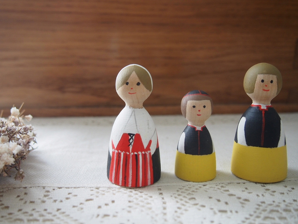 ハンドペイントで仕上げられたスウェーデンの木製フォークロア人形3体をテーブルに並べた画像。素朴であたたかな風合いの北欧雑貨。 antenna