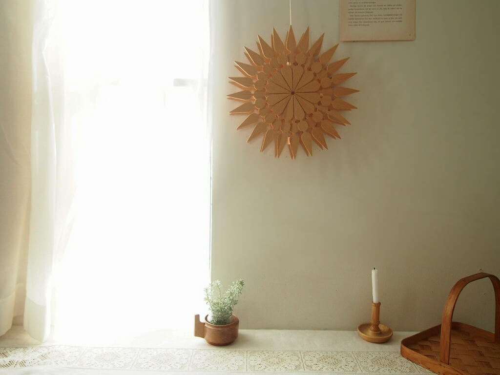 壁に吊るしたオーナメント。光に照らされ木目の陰影がやわらかく浮かぶ様子。 antenna