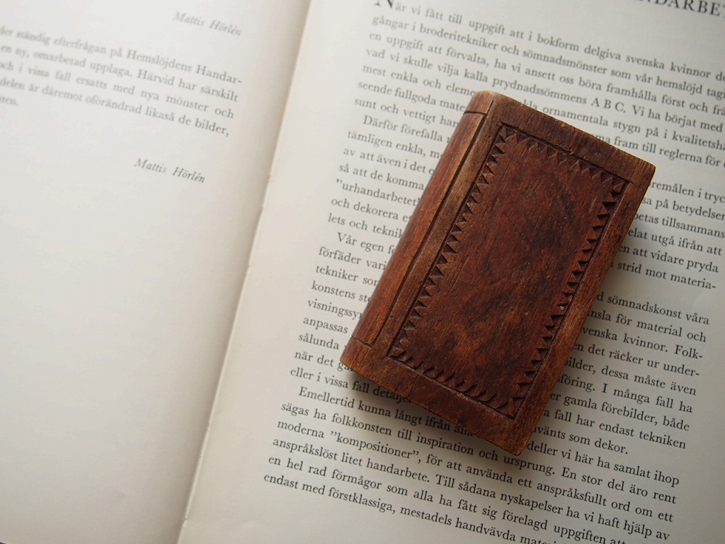 本の形をしたスウェーデン製木製小物入れを開いた本の上に置いた様子。 antenna