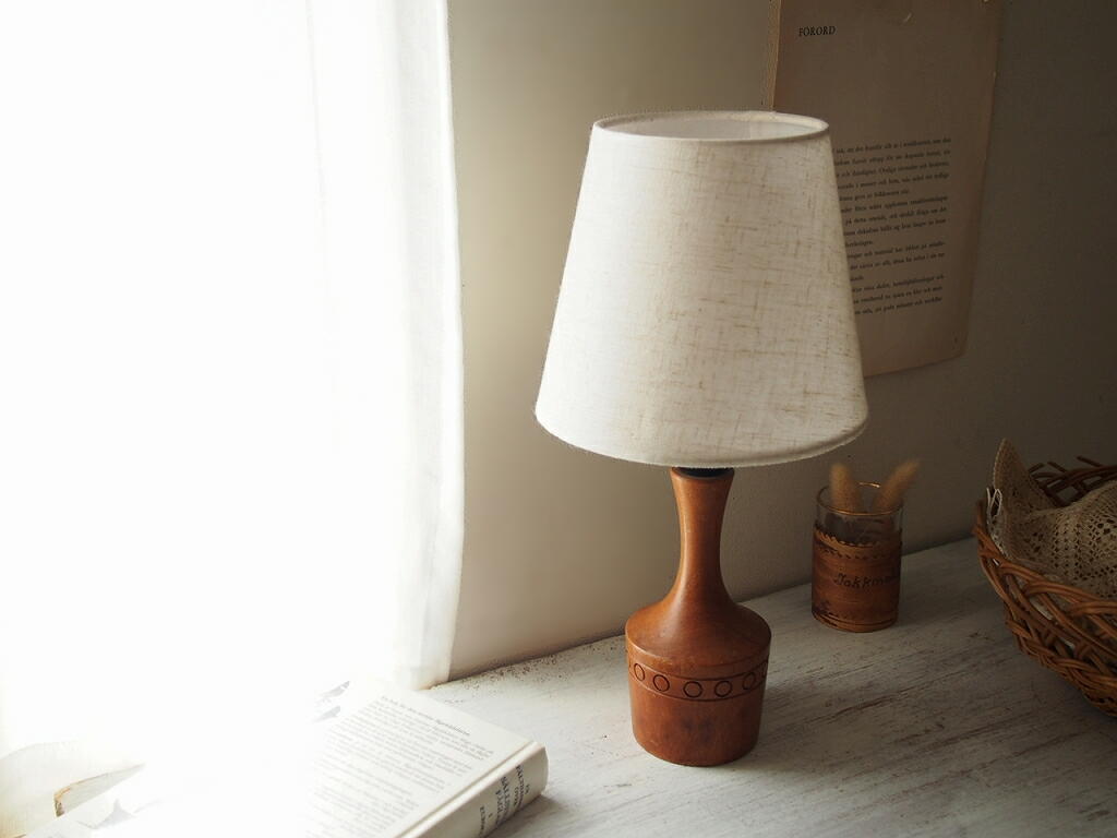 窓辺で自然光の中に置かれたチーク材のテーブルランプ。 antenna