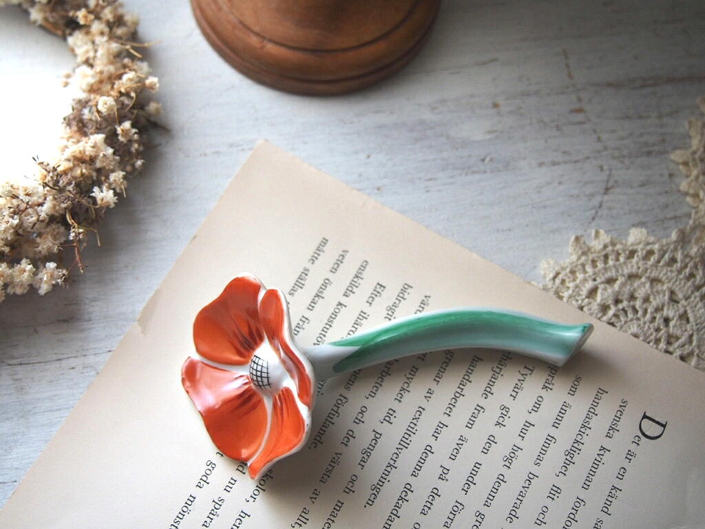 オレンジの花のカトラリーレストを本の上に置いた北欧ヴィンテージ写真。 antenna