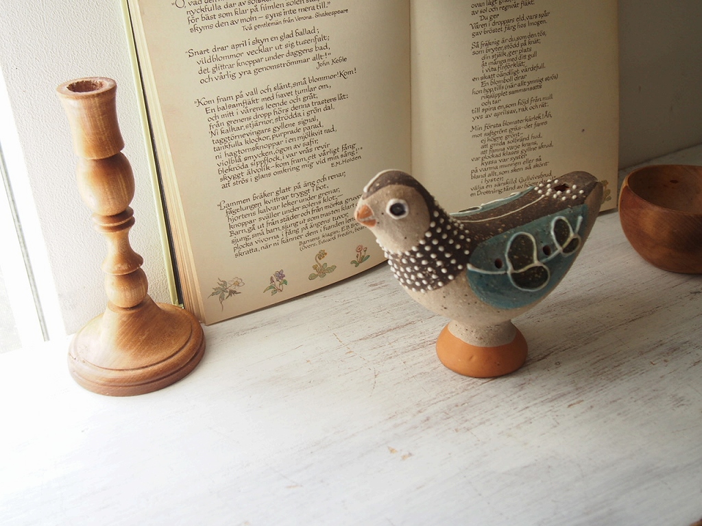 窓辺で本と一緒に置かれたNittsjo鳥の陶器オブジェ。 antenna